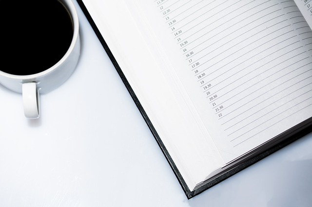 Kalendarz i kubek z kawą na białym biurku